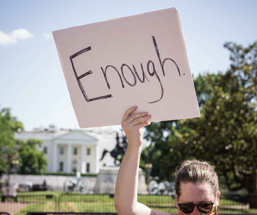 photo of a person holding a sign up in front of the White House