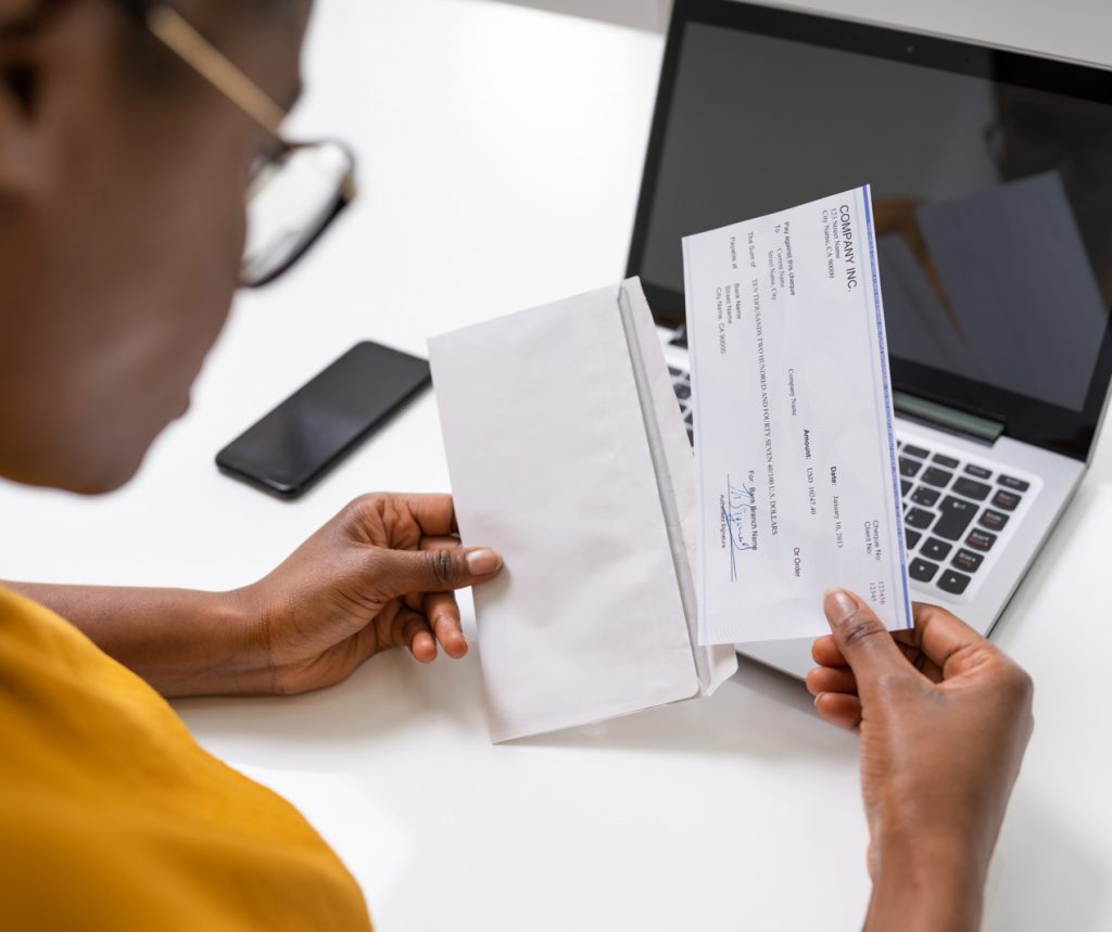 photo over the shoulder of a woman removing her paycheck from an envelope