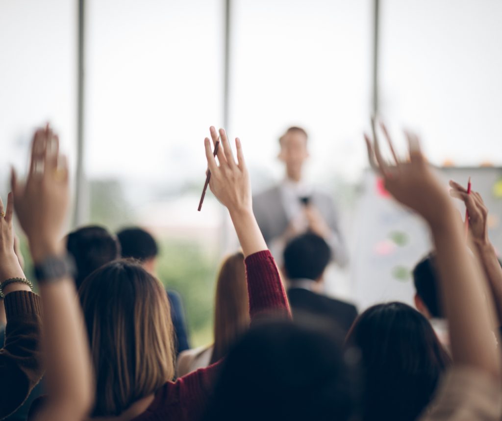 photo of concerned parents raising their hands at a meeting